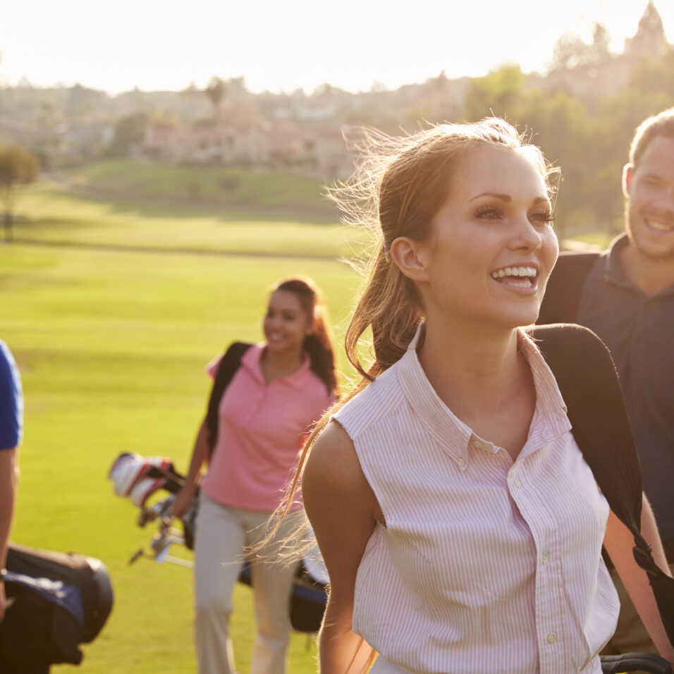 Un groupe de golfeurs marchent sur un terrain et portent des clubs de golf