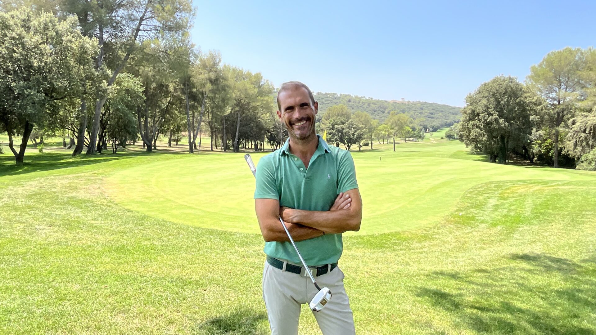 Romain Dury, coach de golf, devant une zone de putting avec des arbres