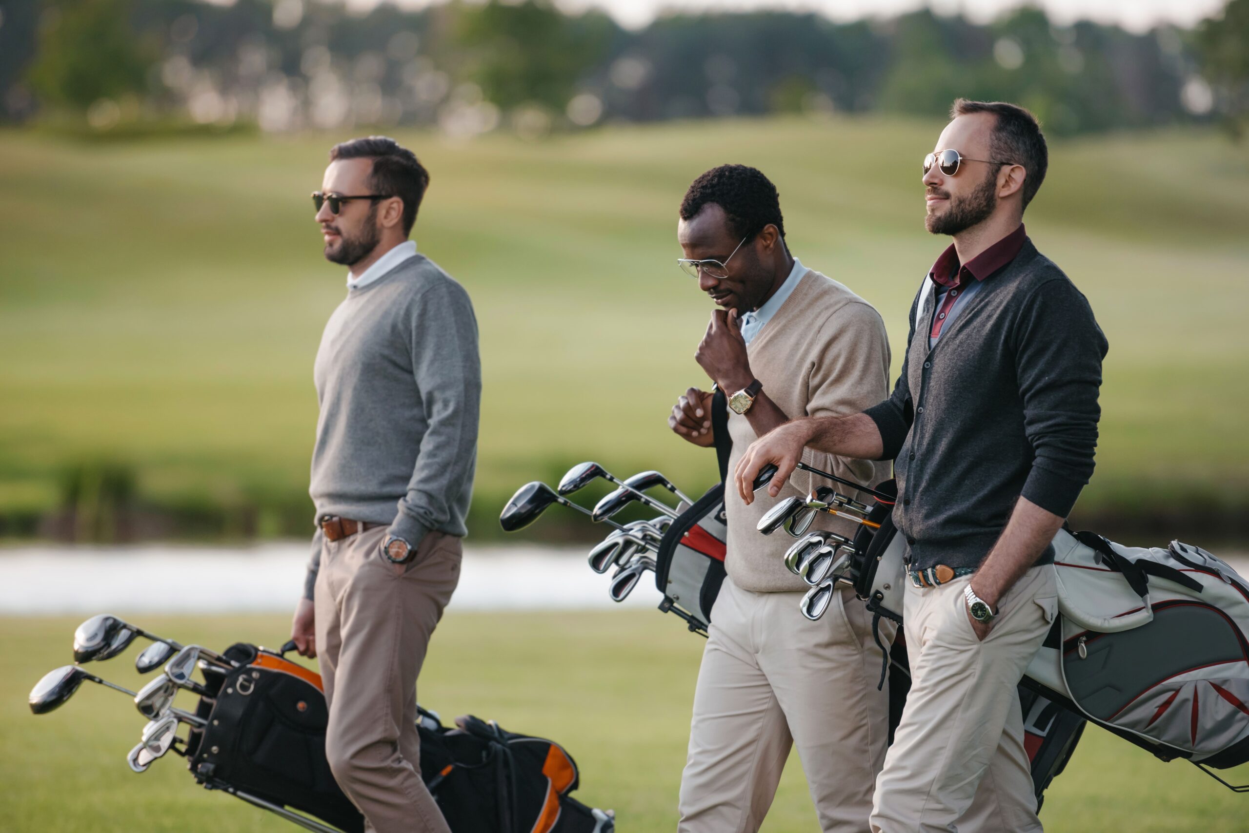 Un groupe d'amis portent des clubs de golf sur un terrain de golf, de côté